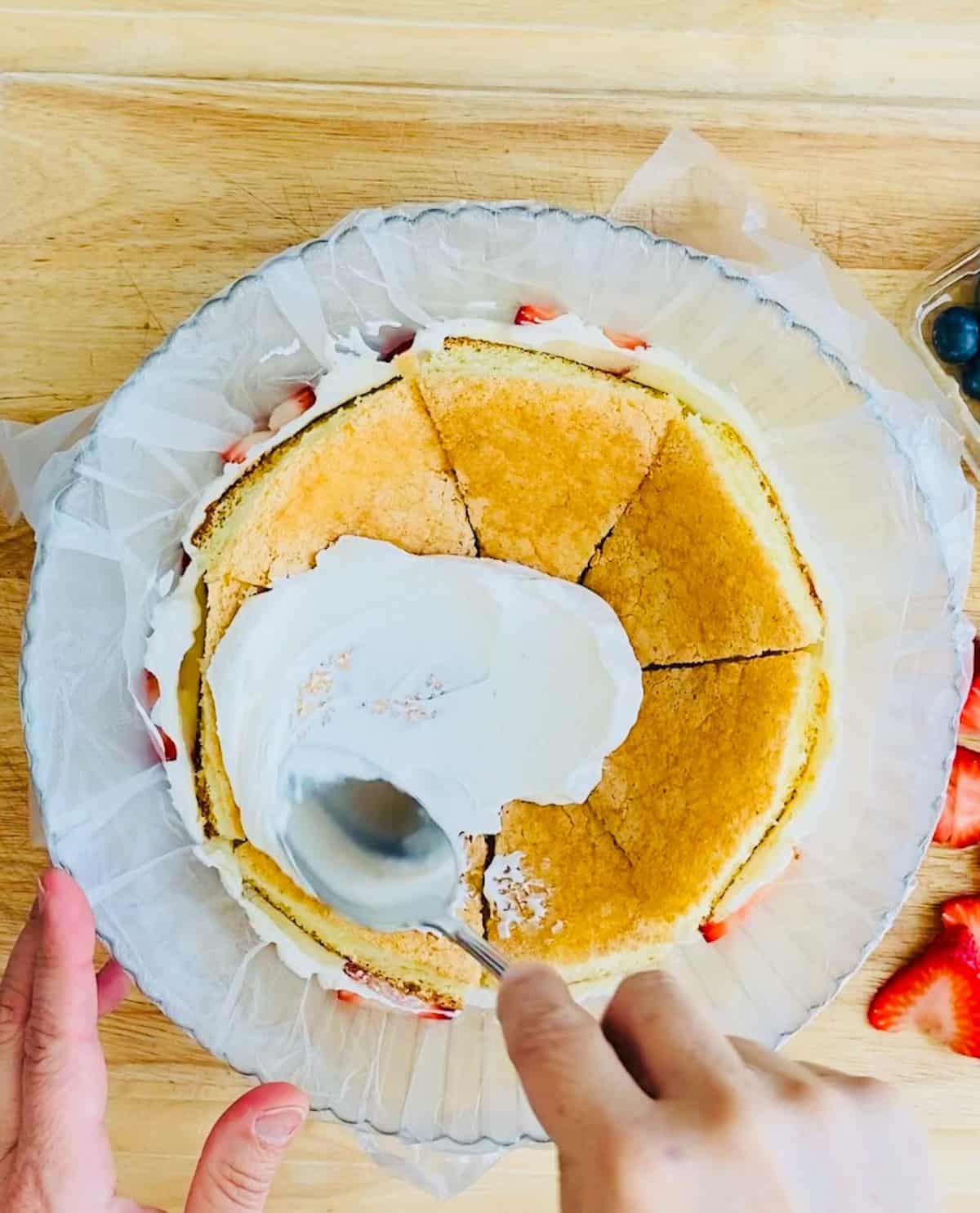 Inside of fruit dome cake with whipped cream being spread on sponge cake layers
