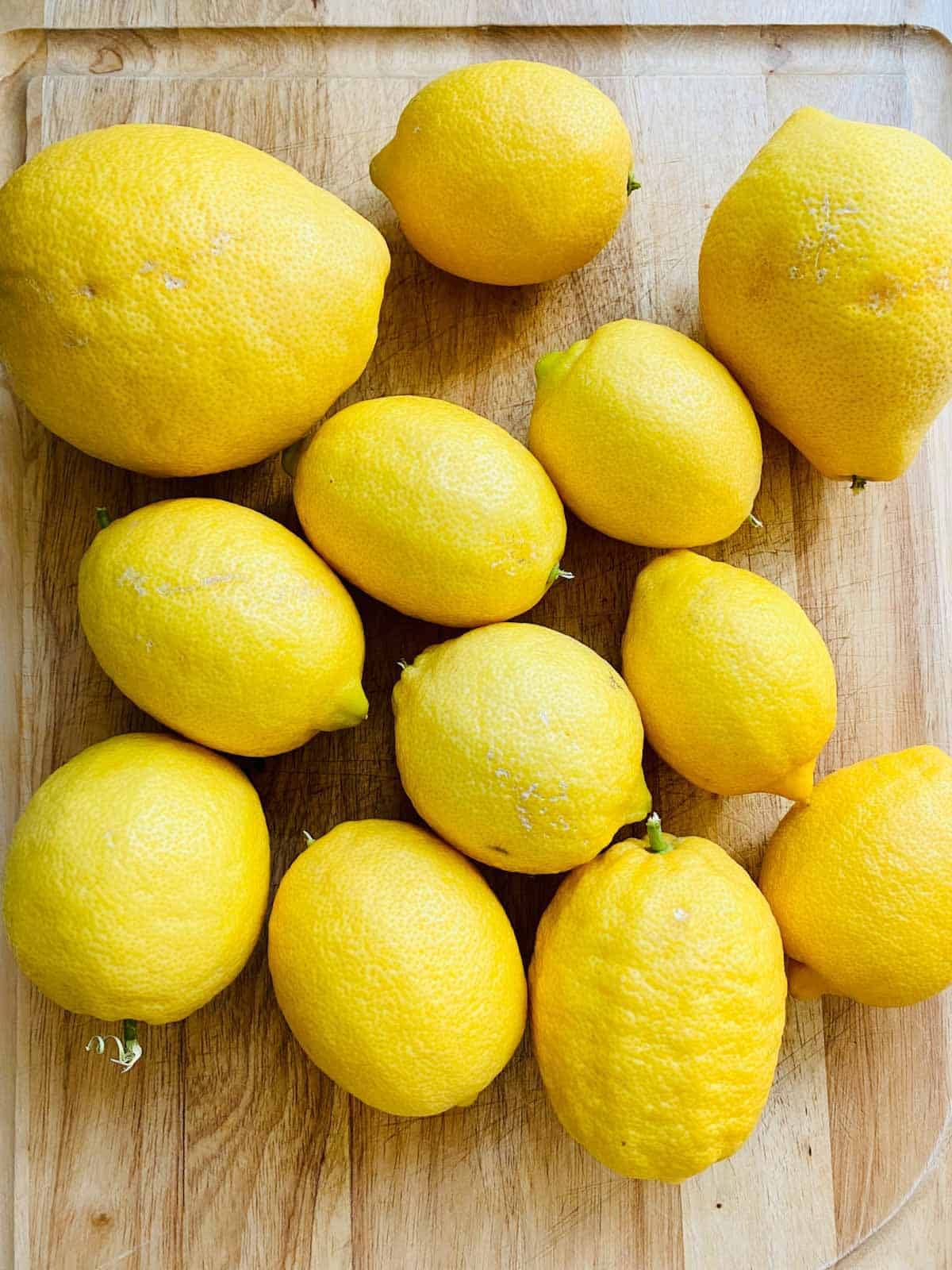 Twelve whole lemons on a cutting board