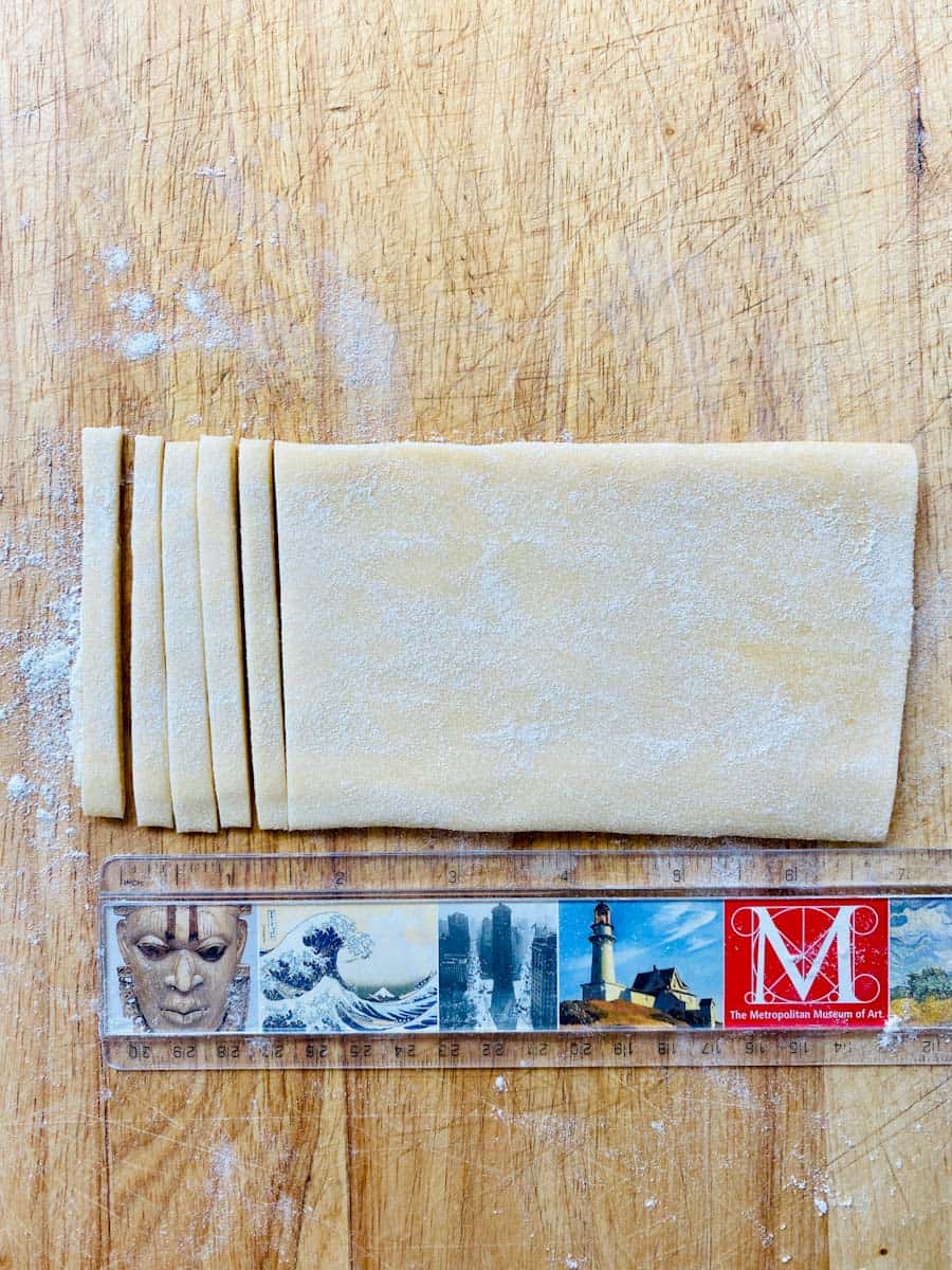 Folded sheet of pasta next to a ruler showing width of noodles
