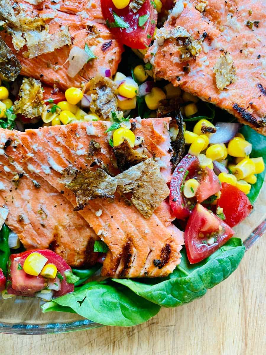 Close up of grilled salmon on corn and tomato salad