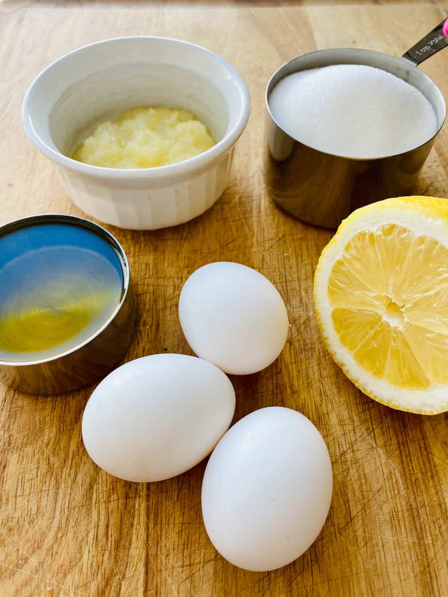 Eggs, oil, sugar, preserved lemon paste all on a wooden cutting board