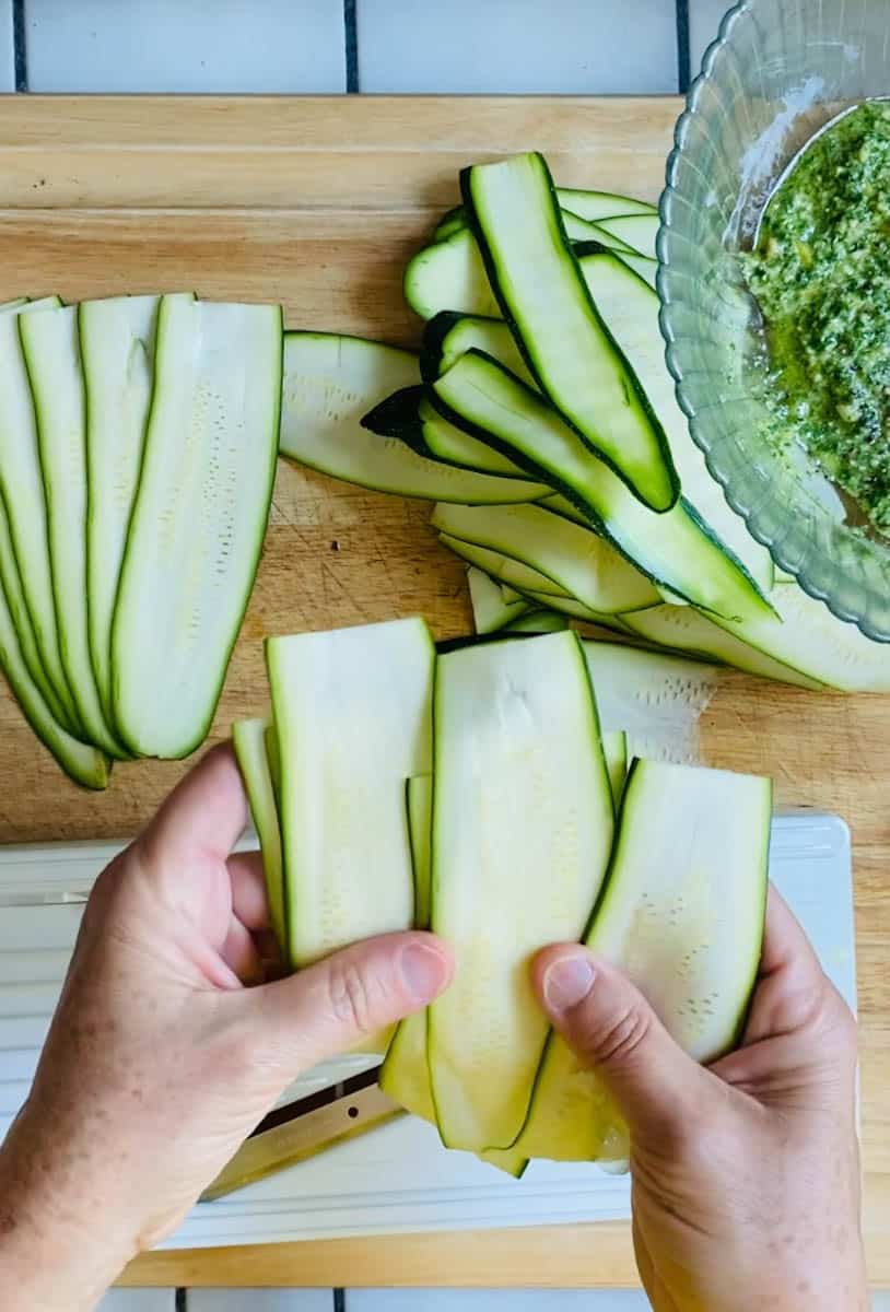 Thin slices of zucchini on a wooden cutting board and in my hands