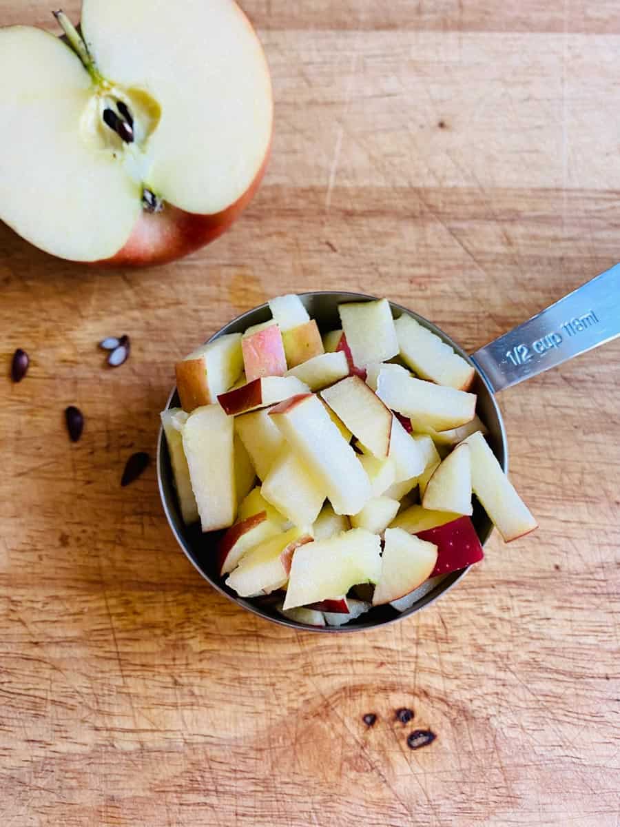 Chopped apple in a measuring cup and apple half next to it