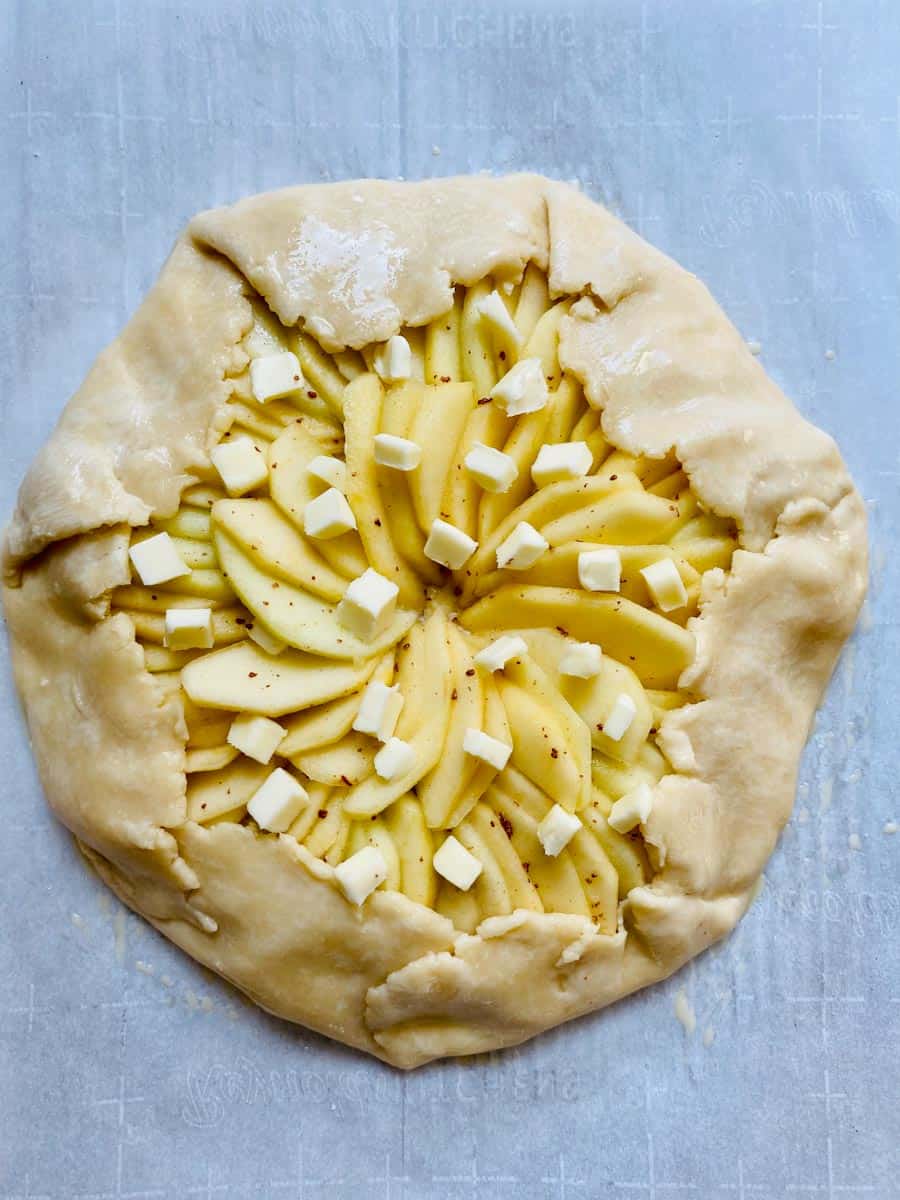 Apple galette assembled, folded, egg washed, and dotted with butter. It's ready for the oven!
