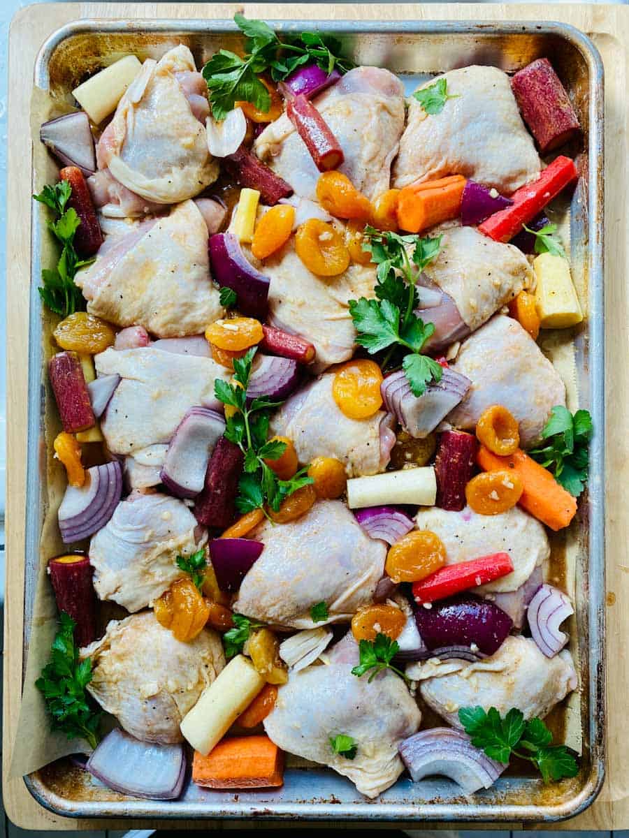 Tzimmes chicken and apricots prepped on a sheet pan and ready for roasting.