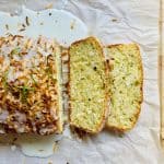 Zucchini bread with first two slices laying flat surrounding by a pool of delicious lime glaze