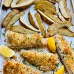 Sheet Pan Fish and Chips with lemon wedges.