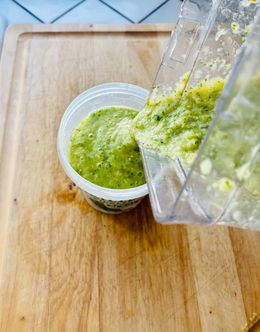 A blender filled with salsa on a cutting board.