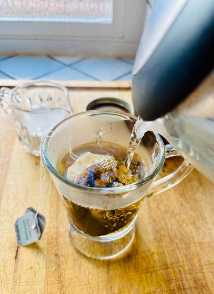 Adding hot water to tea bags in a mug.