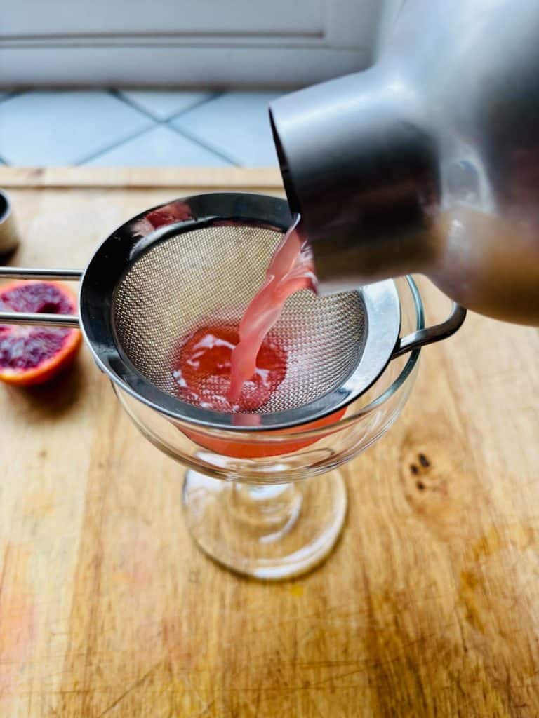 Straining the drink into a glass.