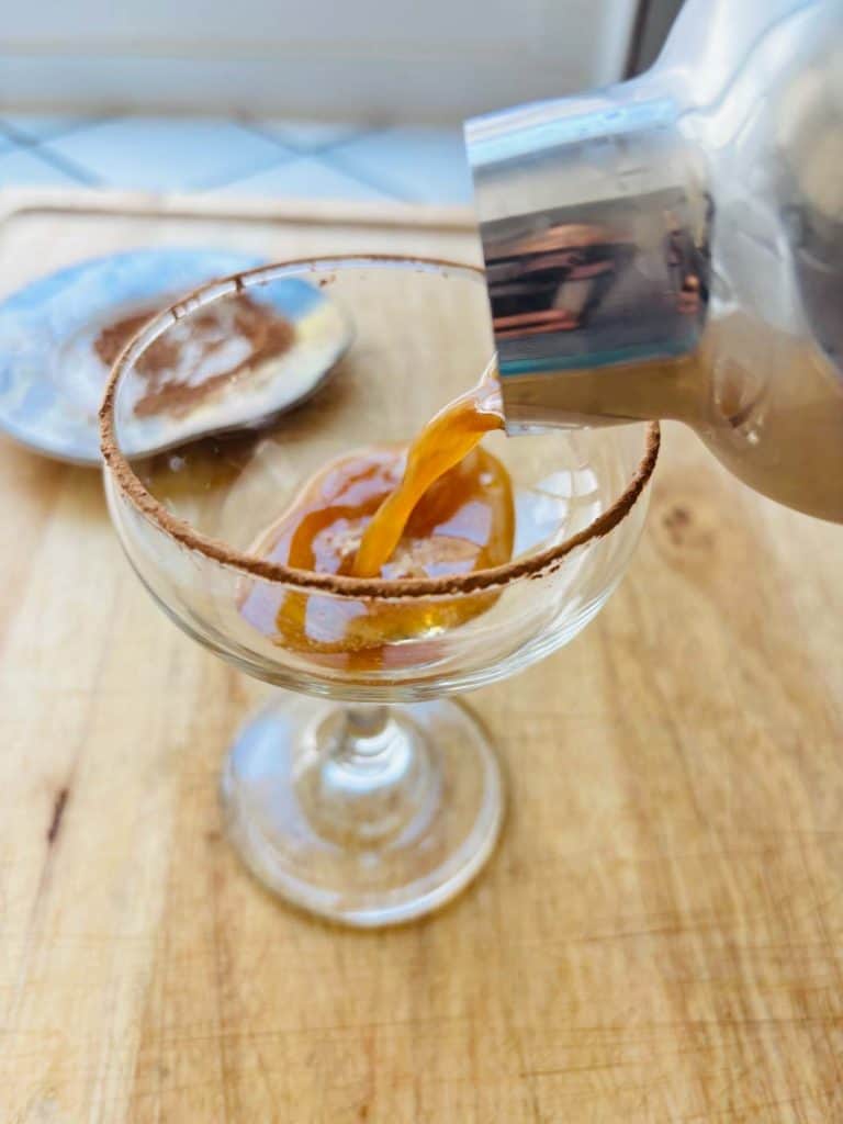 Straining the mocktail into a cocktail glass.
