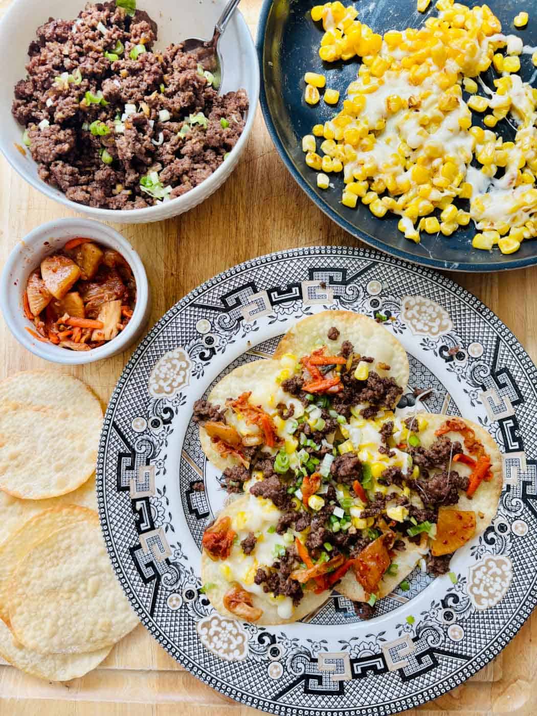 Korean Nachos assembled with crispy chips, kimchi, ground beef, and cheesy corn.