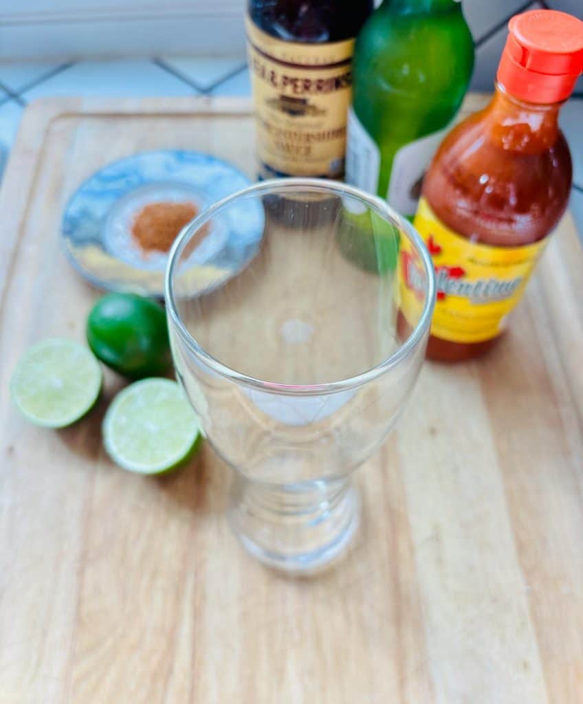 Michelada ingredients: Tajin, Worcestershire sauce, beer, Valentina hot sauce, and lime.