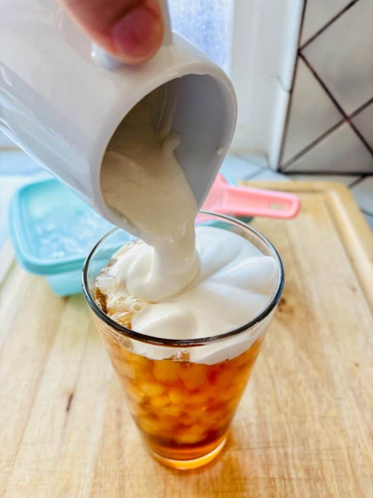 Pouring the cream over the iced tea.