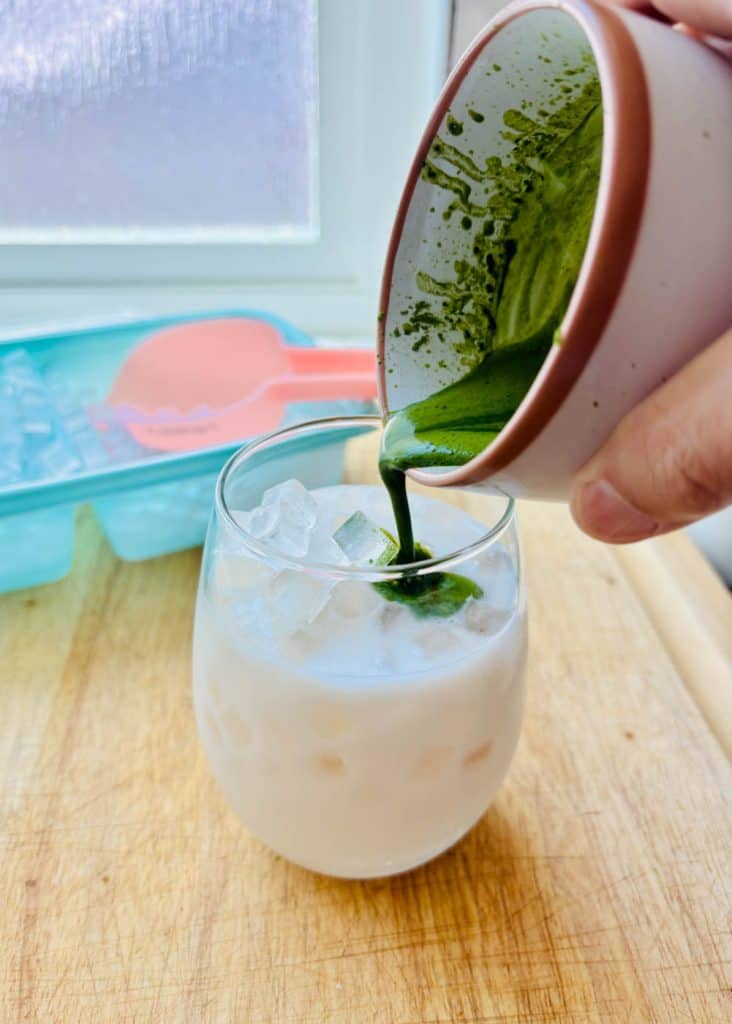 Pouring matcha over iced milk.