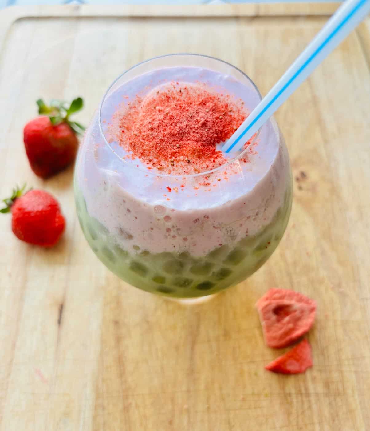 Iced strawberry matcha latte with straw.