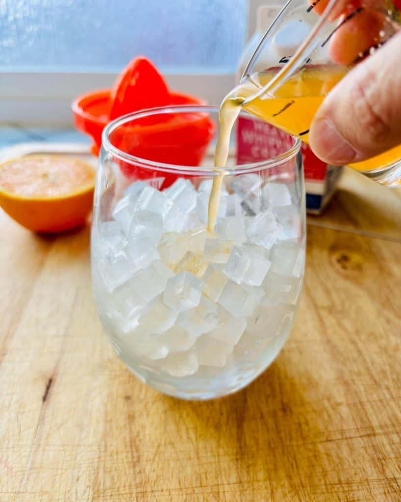 Pouring in the orange juice.