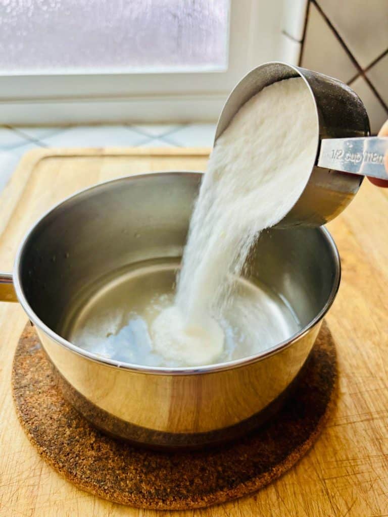 Tipping sweetener into a saucepan.
