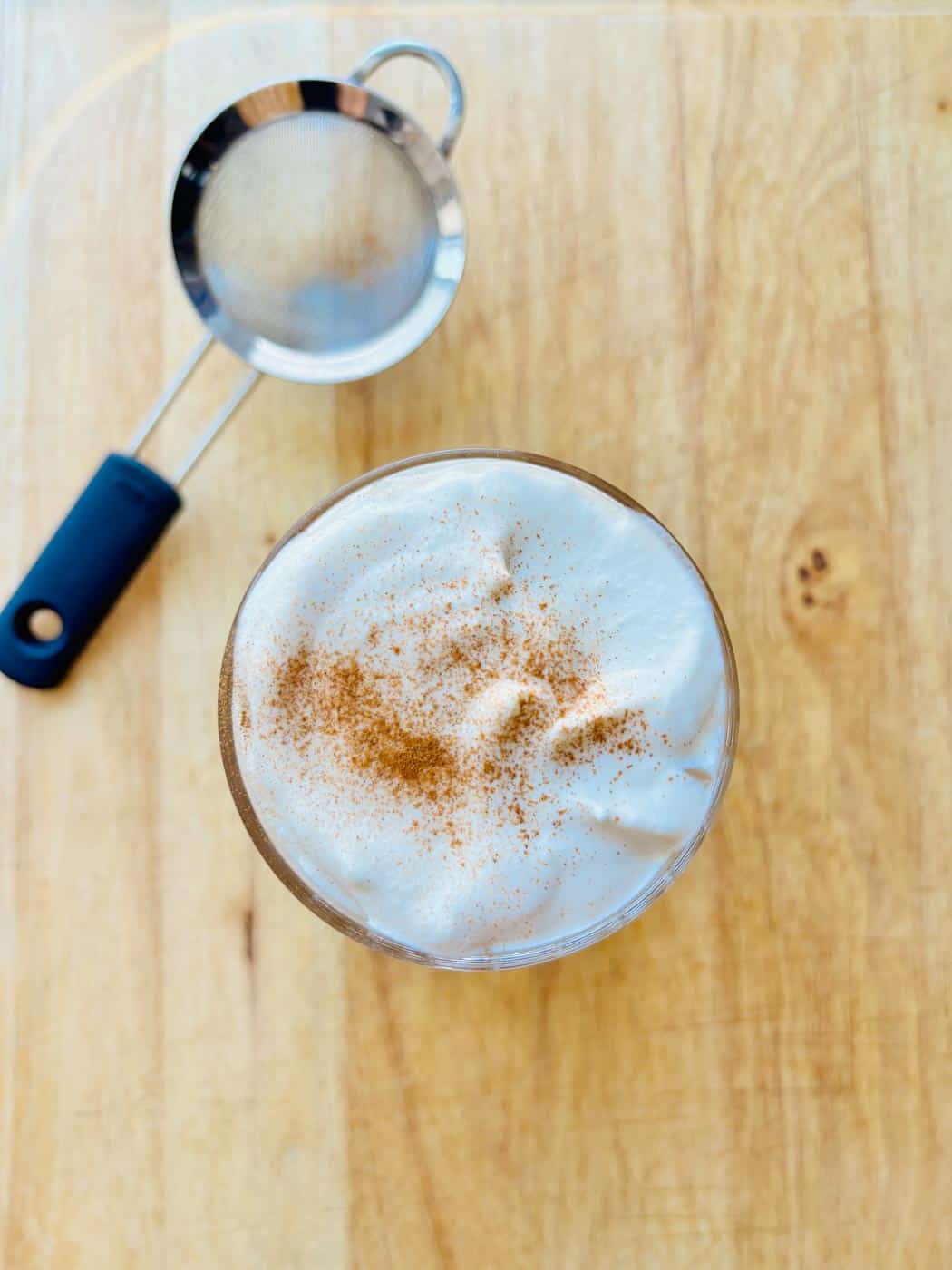 Iced chai latte dusted with ground cinnamon.
