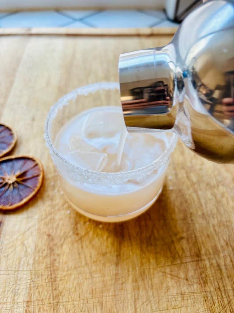 Pouring the cocktail into a glass.
